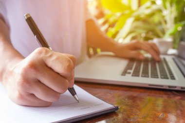 Kalem defter üzerinde elini tuttum ve eller serbest kadın'ın bir kafede klavye dizüstü bilgisayarda yazarak, web arama, tarama / yumuşak odak görüntü dizüstü kullanan kız.