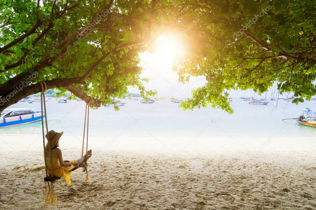 Traveler Asian woman in bikini relaxing on wooden swing and looking at sea, Phi Phi Island, Andaman sea, Krabi, Travel in Thailand, Summer holiday and vacation travel trip.