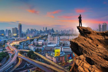 Üstünde tepe-in en yüksek dağ ve ileriye bakarak cityscape arka plan, başarı, rekabet ve lider kavramı ile sarılmak kavramı vizyon, işadamı giyiyor rahat rahat takım elbise ceket ayakta göğsünüze.