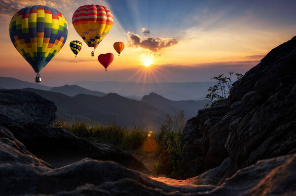 Beautiful colorful hot air balloons flying over mountain at view point Sunset of travel place, Doi Pha Tang, Chiang Rai's Hidden Paradise in Thailand.