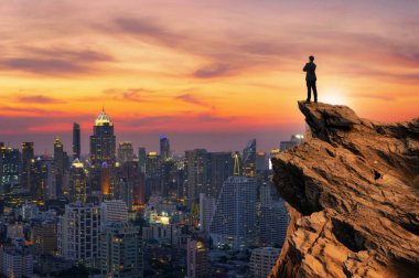 Üstünde tepe-in en yüksek dağ ve ileriye bakarak cityscape arka plan, başarı, rekabet ve lider kavramı ile sarılmak kavramı vizyon, işadamı giyiyor rahat rahat takım elbise ceket ayakta göğsünüze.