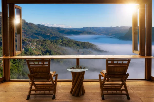 wooden table and chairs on terrace against beautiful mountain landscape view in cafe at sunrise