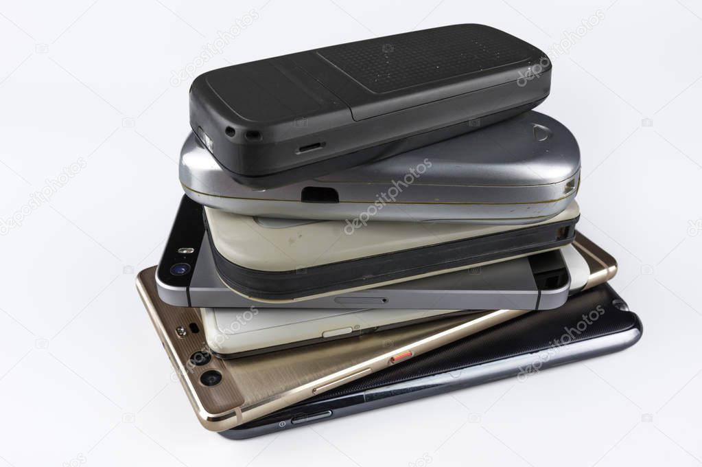 Stack of high-end smartphones on white desk.