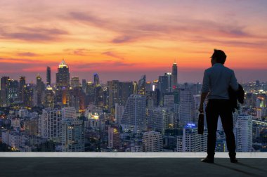 Kavram vizyon, bina ve manzarası modern binalarda bakarak en üstünde duran rahat rahat takım elbise giymiş genç işadamı.