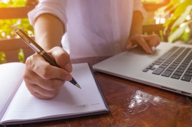 Kalem defter üzerinde elini tuttum ve eller serbest kadın'ın bir kafede klavye dizüstü bilgisayarda yazarak, web arama, tarama / yumuşak odak görüntü dizüstü kullanan kız.