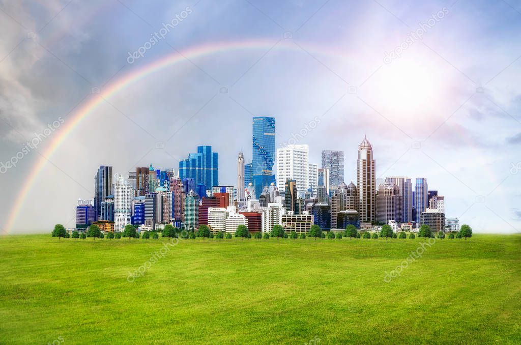 Modern city view with beautiful buildings on green grass, rainbow on sky and the sun, Green city concept.