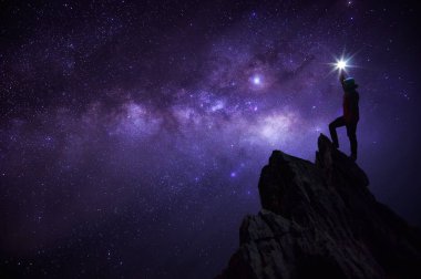 Siluet dağcı veya backpacker, o yıldız dik başını düzenlenen. Kayalık dağ tepe samanyolu galaksi, yıldız ve Uzay tozu evren, başarı, lider kavramı karşı üzerinde duran.