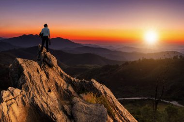 Kavram görme, genç işadamı giyiyor rahat rahat takım elbise ceket ayakta iş ihale en yüksek dağın tepesinde ve ileriye bakarak, başarı, rekabet ve lider kavramı.