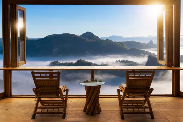 wooden table and chairs on terrace against beautiful mountain landscape view in cafe at sunrise