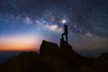 Siluet dağcı veya backpacker kayalık dağ tepe ve Samanyolu Gökadası, başarı, kazanan, lider kavramı