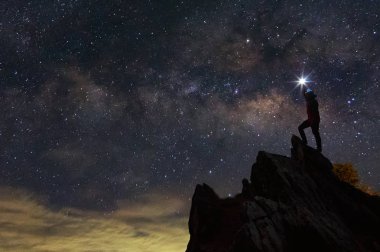 Siluet dağcı veya backpacker kayalık dağ tepe ve Samanyolu Gökadası, başarı, kazanan, lider kavramı