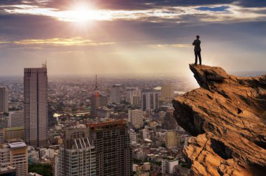 Dağ tepe üstünde duran ve ileriye arıyorum cityscape arka plan, başarı, rekabet ve lider kavramı ile rahat rahat giyen işadamı kavramı vizyon, uygun.