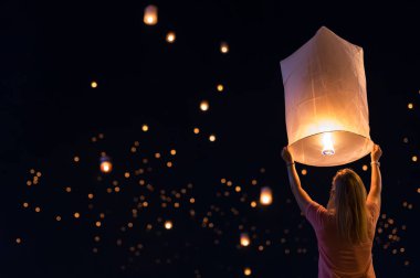 Woman releasing floating lanterns in the Loy Krathong festival or floating lanterns festival in Chiang Mai, Thailand. clipart
