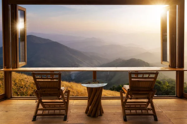 wooden table and chairs on terrace against beautiful mountain landscape view in cafe at sunrise