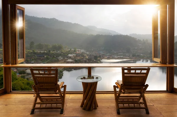 Beautiful landscape at cafe style minimal with wood tables and chairs on terrace against the outdoor lake view in cafe at sunrise.