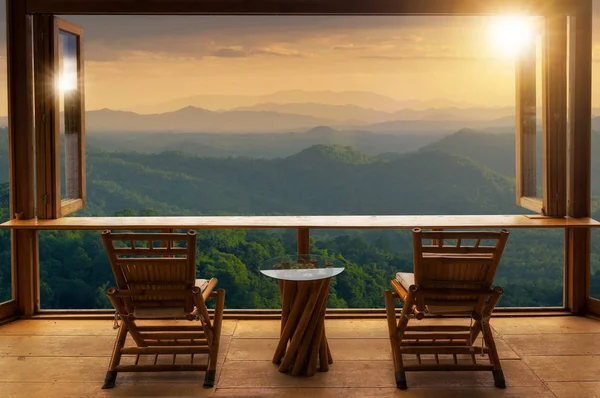 wooden table and chairs on terrace against beautiful mountain landscape view in cafe at sunrise