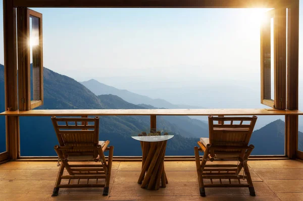 Beautiful landscape at cafe style minimal with wood tables and chairs terrace against the outdoor Mountain view in cafe at sunrise.