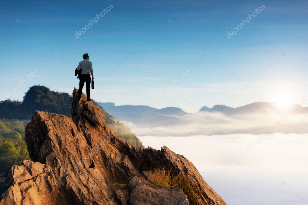 Concept vision, Young businessman wearing comfortable casual suit jacket standing on top of mountain peak and looking forwards, success, competition and leader concept.