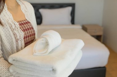 Genç otel hizmetçisi çarşaf ve yumuşak havlu temiz oda tutar. 