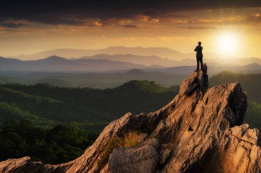 Kavram vizyon, genç işadamı giyiyor rahat rahat takım en yüksek dağın tepesinde duran ve ileriye bakarak, başarı, rekabet ve lider kavramı.