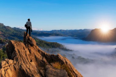 Concept vision, Young businessman wearing comfortable casual suit standing on top of mountain and looking forwards, success, competition and leader concept.