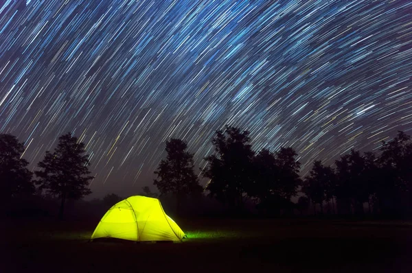 Glowing Yellow camping tent under night sky with stars