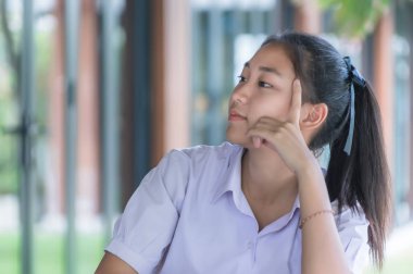 kahve dükkanında otururken üniforma rahatlatıcı genç Asya Kolej öğrencisi, eğitim konsepti.