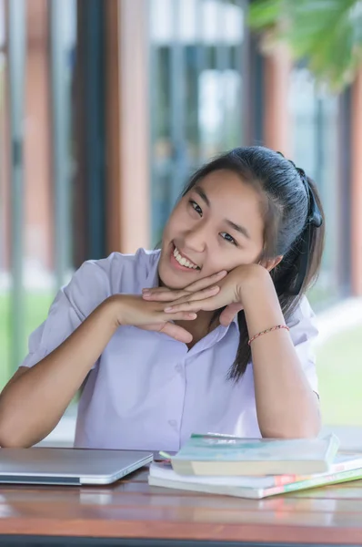 young asian college student in uniform relaxing while sitting at coffee shop, education concept.