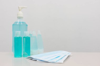 Coronavirus Önleme Ekipmanı, Tıbbi Maskeli El dezenfektanı beyaz masada. Hastalığın başkalarına bulaşmasını önlemek için kampanya mesajı eklemek için boş bir alan..