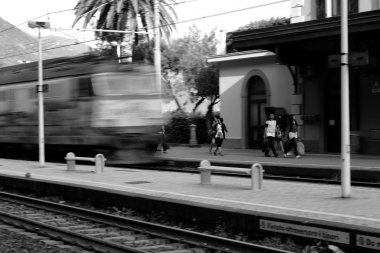 Vernazza tren istasyonu Liguria, İtalya'da yerel bir tren servisi yaklaşırken yolcuları bekleyen bir platform. Siyah Beyaz.