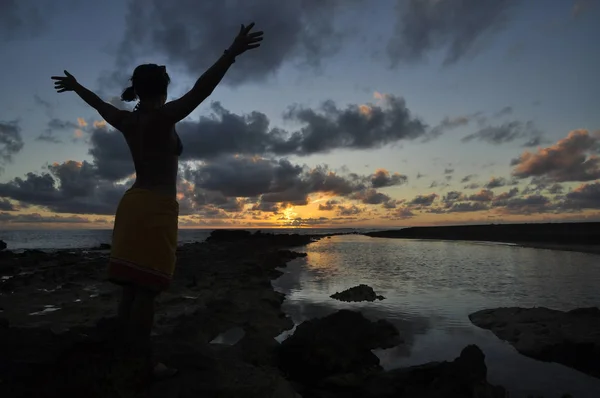 Woman give the sun salutation during sunset.