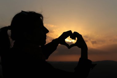 Elleriyle kalp şeklinde bir siluet.