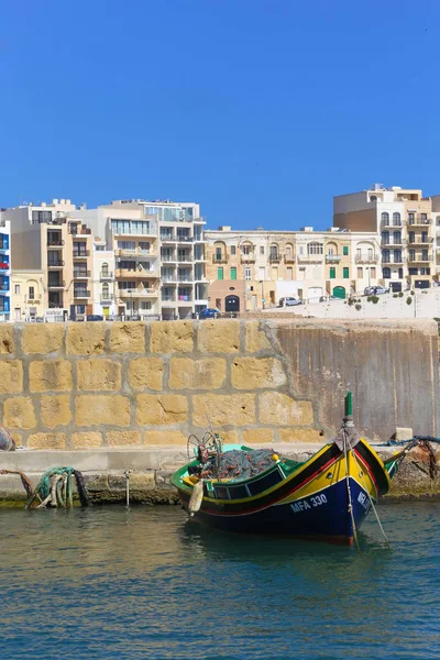 Traditional Maltese boat and new constructions int he background. Gozo. Malta