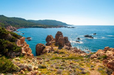 Sardinya 'daki Costa Paradiso plajında, turkuaz mavi denizli pembe kaya granitik oluşumu.