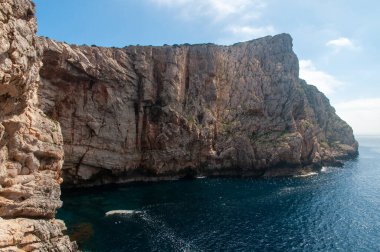 Capo Caccia kıyısında mavi denizli beyaz bir uçurum. Sardunya, İtalya