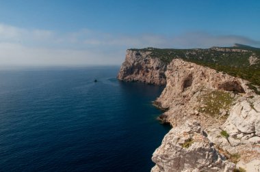 Capo Caccia kıyısında mavi denizli beyaz bir uçurum. Sardunya, İtalya
