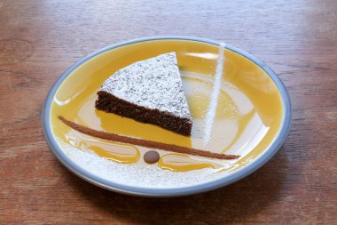 Bir dilim çikolatalı pasta, buz şekeri ve ahşap masadaki tek tabakta süsleme.