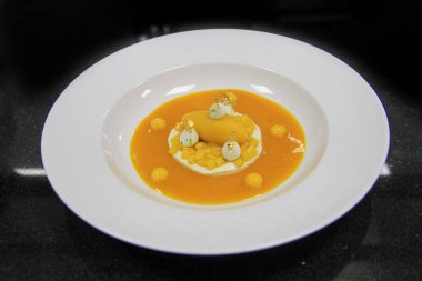 Yüksek mutfak tatlısı, siyah arka planda, beyaz kremalı jöleli mango meyveli mango dondurması. İzole edilmiş seramik beyaz tabakta 45 derecelik açı.. 