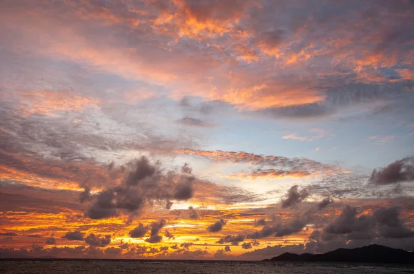 stock image Beautiful tropical sunset over the sea horizon with black silhouette of an island. Seychelles