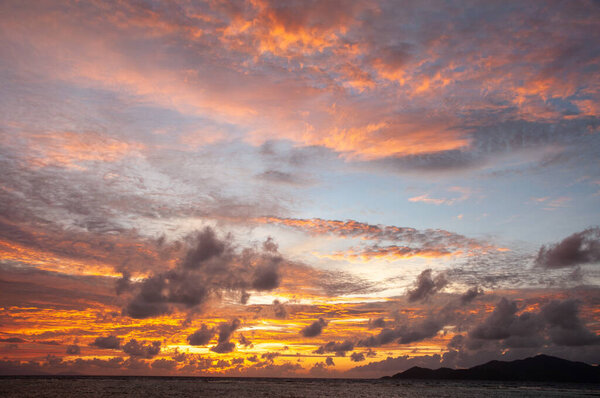 Закат над морем с черным силуэтом острова. Сейшельские острова