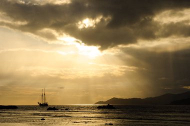 Gün batımında yelkenli tekneyle Hint Okyanusu üzerinde bulutlar ve güneş ışığıyla dramatik bir gökyüzü..