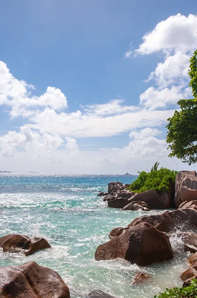 Güneşli bir tropikal günde ufukta ufuk çizgisi olan kayaların üzerinden akan deniz suyu. Anse Songe, La Digue Adası, Seyşeller
