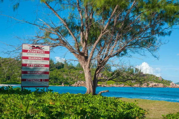 Warning sign post of strong current at the beach of Anse Cocos, La Digue island, Seychelles