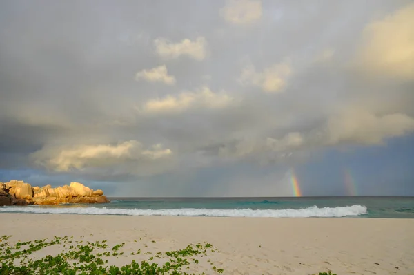 塞舌尔 拉迪古岛 热带海滩上 五彩缤纷的彩虹掠过大海 波浪和岩石笼罩在暴风雨的天空之下 — 图库照片