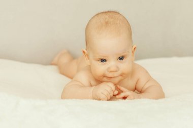 Sevimli erkek bebek yüzüstü yatıp gülümsüyor. Sıcaklık ve yaşam tarzı kavramı