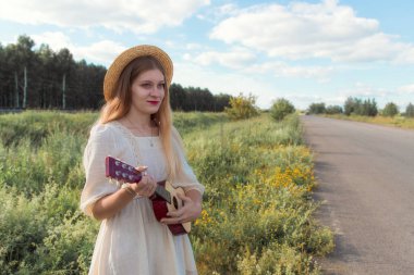 Şapkalı kız çiçeklerle kurumuş çayırlarda yürüyor.