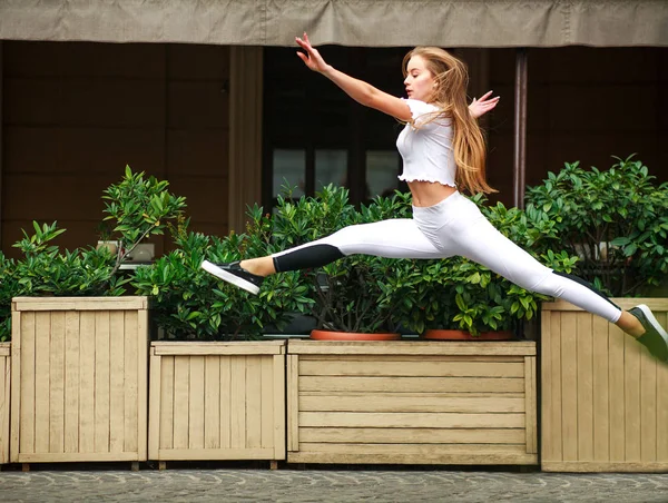 运动女孩体操运动员跳在飞行中的街道房子的门面 — 图库照片