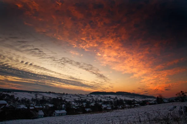 Colorful sunset in winter over hills and forests in the countryside village