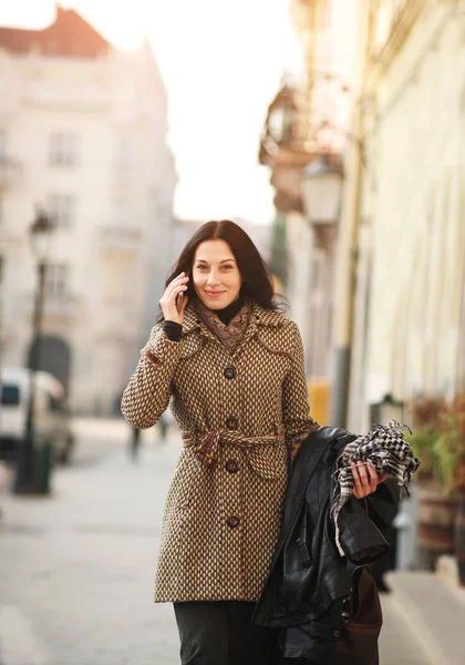 Радостная девушка в классическом платье разговаривает на мобильном телефоне на городской улице — стоковое фото