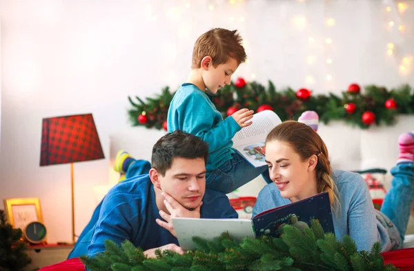 Счастливая Молодая Семья Сыном Рождество Читают Книгу Вместе Дома — стоковое фото